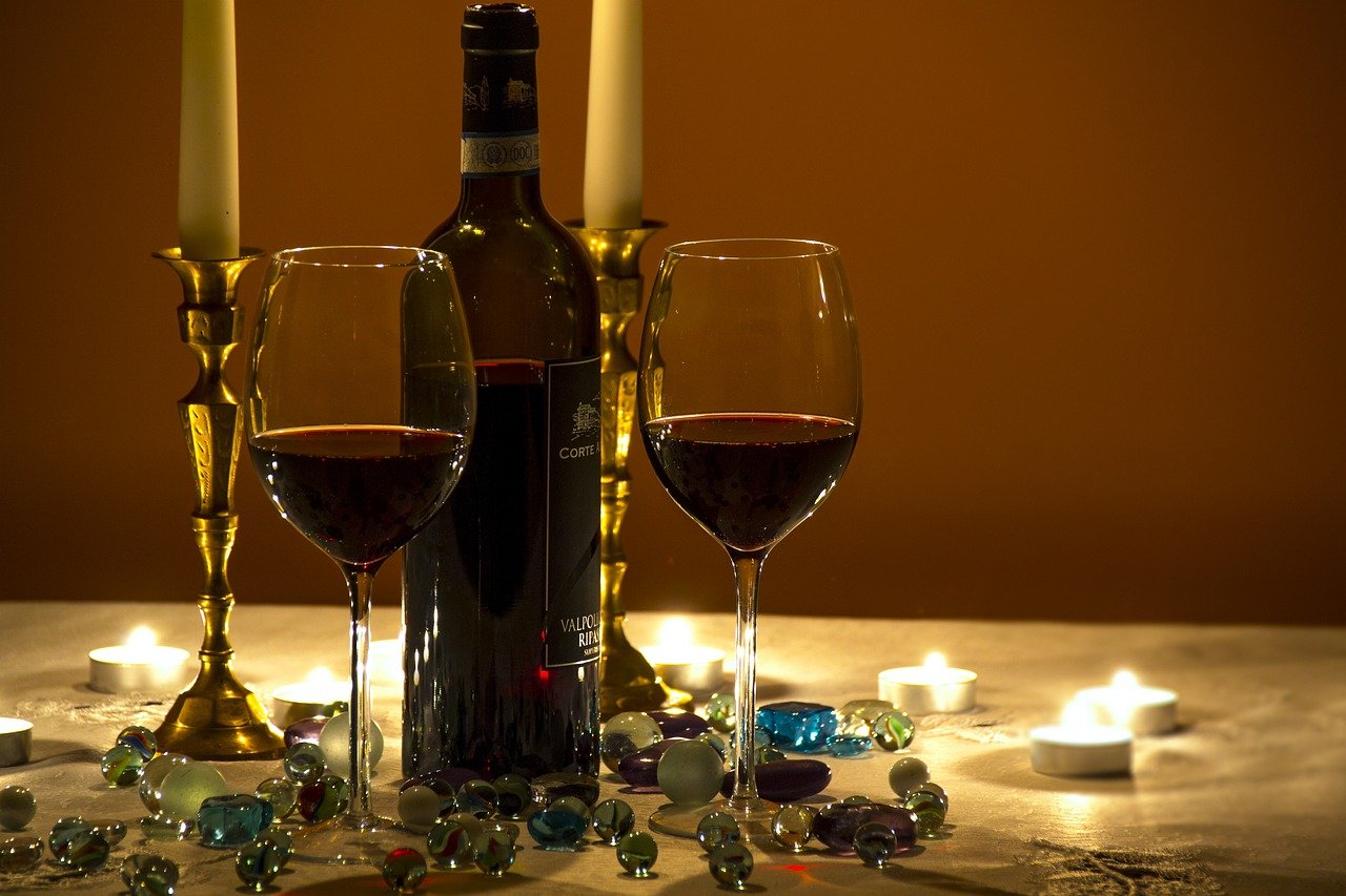 Bottle of wine & two half filled glasses on a candlelit table.